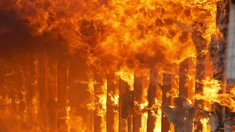 Slow motion flames engulfing a small building. House wall being burned down by a Stock Footage 229819158