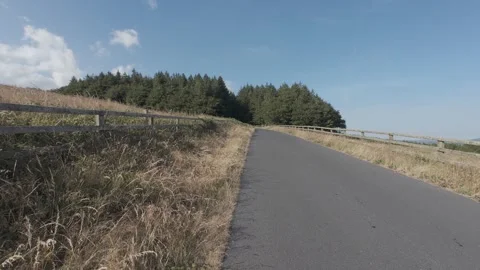 Slow motion flat color empty asphalt country road through hills Stock Footage 340449239