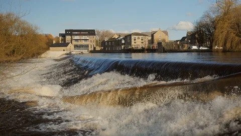 Slow Motion of a flooded UK river creating a heavy waterfall downstream. Vídeo Stock 125582893