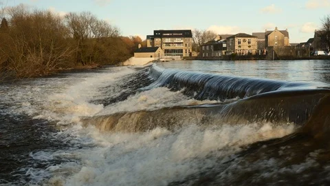 Slow Motion of a flooded UK river creating a heavy waterfall downstream. Vídeo Stock 125586949
