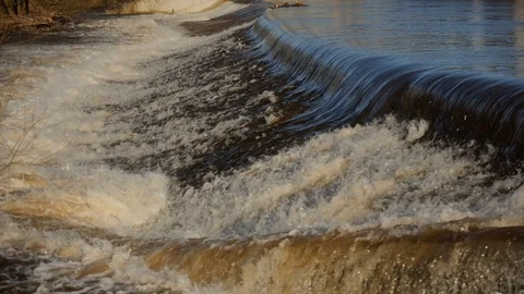 Slow Motion of a flooded UK river creating a heavy waterfall downstream. Vídeo Stock 125587008