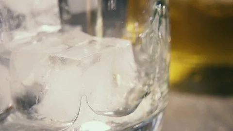 Slow motion the flow of amber drink on the ice cube in a glass Stock-Footage 94032261