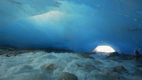 Slow Motion of Flowing Stream Underneath Large, Blue Tinted Glacier, Cave At End Stock Footage 113948642
