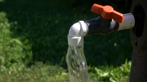 Slow motion of flowing water from an open tap on green grass Stock Footage 115502547
