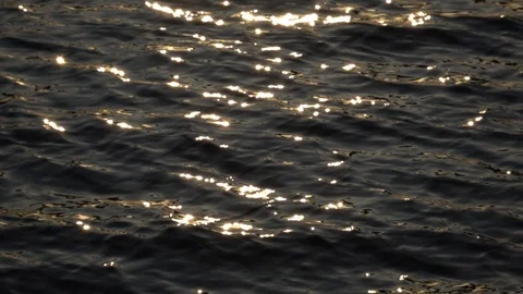 Slow motion of fluent ripple on dark water surface with sun flare reflection. Stock Footage 124304490