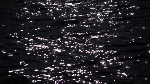 Slow motion of fluent ripple on light defocused dark water with sun reflection. Stock Footage 119885108