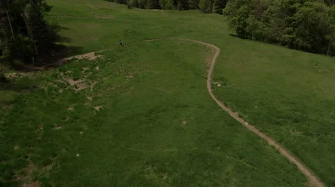 Slow motion fly over as a mountain biker rides along mountain trail Stock Footage 52497294