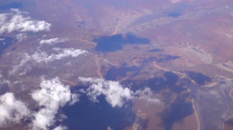 SLOW MOTION: Flying high above white clouds over the vast brown sand desert Stock Footage 64977547