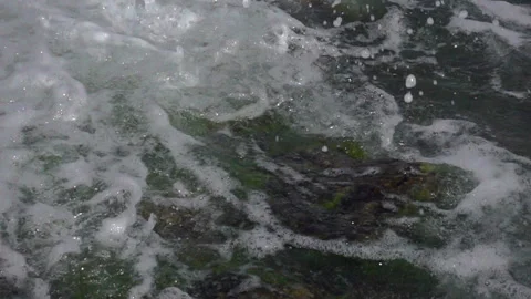 Slow motion foam wave washes the stones in the water on the coast Stock Footage 112365635