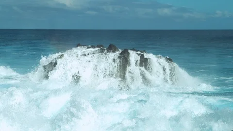 SLOW MOTION: Foaming seawater flows down a big black rock in emerald ocean. Stock Footage 91224429