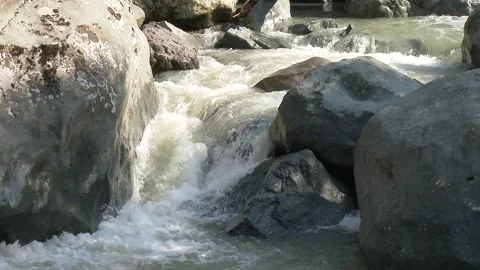 Slow-motion foamy water flows around round oval - Stone Texture and Smooth Rock Stock Footage 339342388