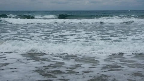Slow motion of foamy waves falling towards sand beach under low the sunlight Stock Footage 234033660