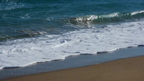 Slow motion of foamy waves falling towards sand beach under low the sunlight Stock Footage 234033801