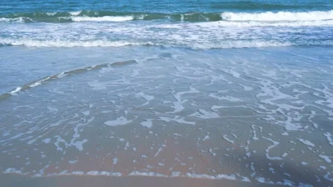 Slow motion of foamy waves rolling towards the sand beach Video stock 221392403
