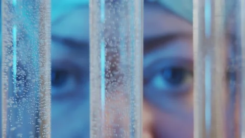 Slow motion focused eyes watching the diffusion of liquids in test tubes in the Stock Footage 233030910