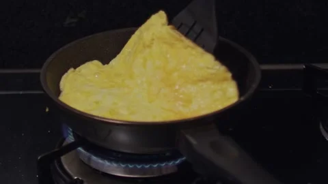 Slow motion, folding omelet with spatula in frying pan at home kitchen. No Stock Footage 209304336