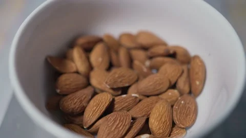 Slow-motion footage of almonds falling into a white bowl Stockbeeldmateriaal 224513010