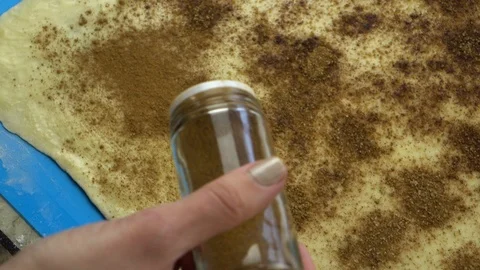 Slow motion footage. Baker hand sprinkling a layer of cinnamon on raw pastry Stock Footage 88452391