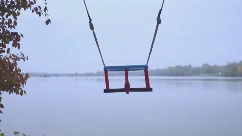 Slow-motion footage of an empty swing swings by the lakeshore Stock-Footage 219727617