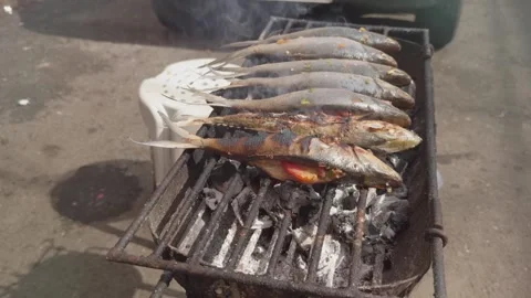 Slow motion footage, fish being grilled on a charcoal grill in a side street. Stock Footage 287093009