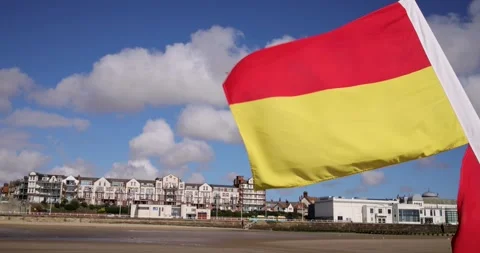Slow motion footage of a large red and yellow beach safety flag fluttering .. Stock Footage 343829393
