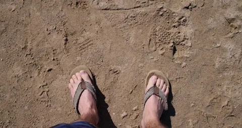 Slow motion footage looking down at a person wearing flip flops while stand.. Stock Footage 343829870