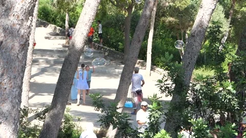 Slow motion footage of man blowing bubbles in park using bubble wand for 스톡 동영상 138410837