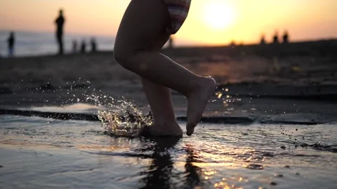 Slow motion footage of a small, bare-legged child running along the edge of the Stock Footage 215676172