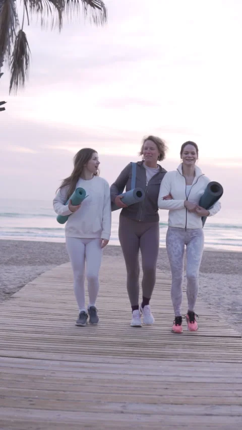 Slow motion footage, three beautiful women in sportswear with yoga mats walking Stock Footage 303410423