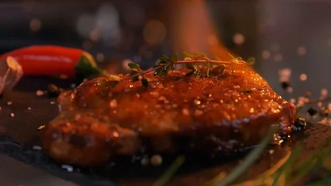 Slow-motion footage of throwing salt and pepper on fresh beef meat on ignited Video stock 107435532