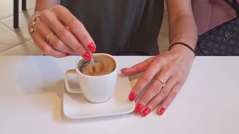 Slow motion footage of the woman adding sugar to her coffee. Beverage Stock Footage 249165181