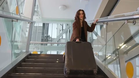Slow motion footage of young elegant woman carrying heavy suitcase up the stairs Stock Footage 170059905