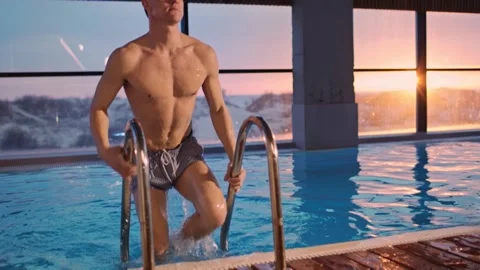 Slow motion footage of a young guy at sunset climbing out of the pool during a Stock-Footage 242011348
