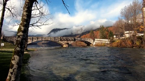 Slow motion forward moving by river bank near famous Bohinj lake bridge Stock Footage 122152501