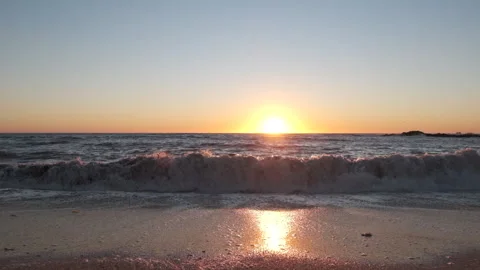 Slow motion forwards movement on beach at sunset, as waves break Video stock 161246278