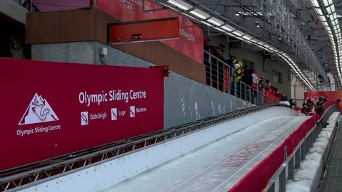 Slow motion of four bobsledders starting their bobsled race by running and Stock Footage 98257822