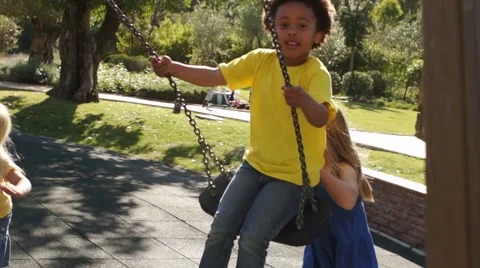 Slow motion of four children playing on swings in park. Stock Footage 43673377