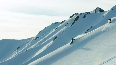 Slow motion of freeride skier and snowboarder riding on powder snow in mountains Video stock 121598030