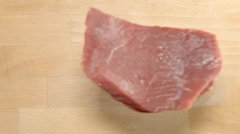 SLOW MOTION: Fresh beef steak falls on a wood plate (top view) Vídeos de archivo 68489714