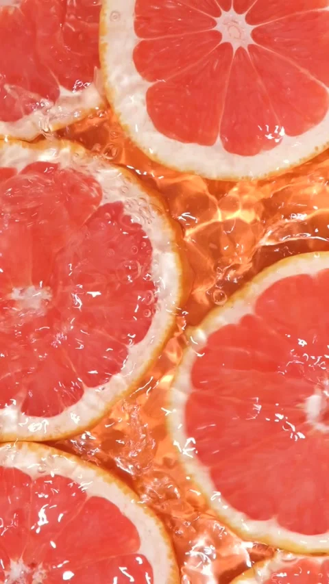Slow motion of fresh grapefruit slices under rippling water with bubbles. Stock Footage 341400479