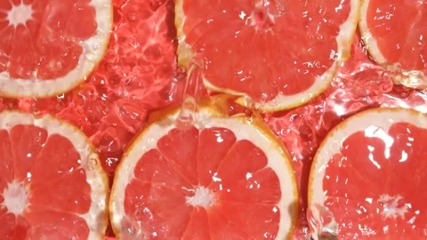 Slow motion of fresh grapefruit slices under rippling water with bubbles Stock Footage 341577321