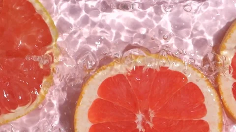 Slow motion of fresh grapefruit slices under rippling water with bubbles. Stock Footage 343003670