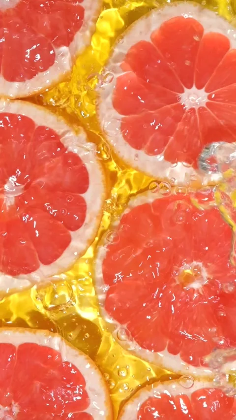 Slow motion of fresh grapefruit slices under rippling water with bubbles. Stock Footage 343003749