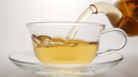 SLOW MOTION: Fresh tea flows in a tea cup from a teapot Stock Footage 70572605