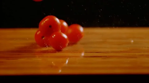Slow motion fresh  tomatoes falling om table from the spray of water Stock Footage 125256748