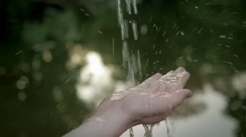 Slow motion of fresh water falling on a hand against the river in the background Stock Footage