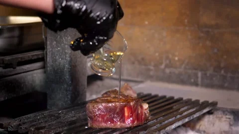 Slow motion. Fried tomahawk steak is sprinkled with oil to make a fire. Stock Footage 154888446