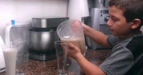 Slow motion of friendly Caucasian cute boy pouring himself juice and milk. Stock Footage 143907438