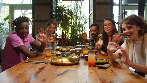 Slow motion, friends sit in a cafe, they wave their hands at the camera and Stock Footage 121930592