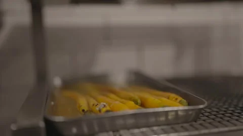 Slow motion front close-up of cooked carrots in metal tray Stock Footage 336366484